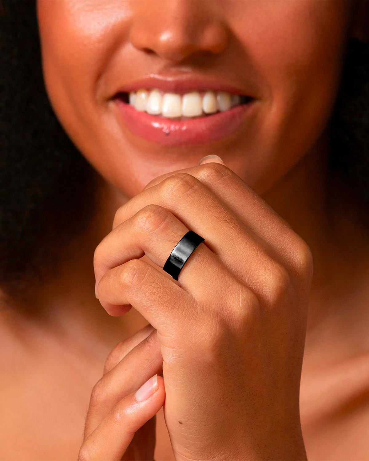 Smiling woman showcasing an Omlezo ring in onyx color on her hand