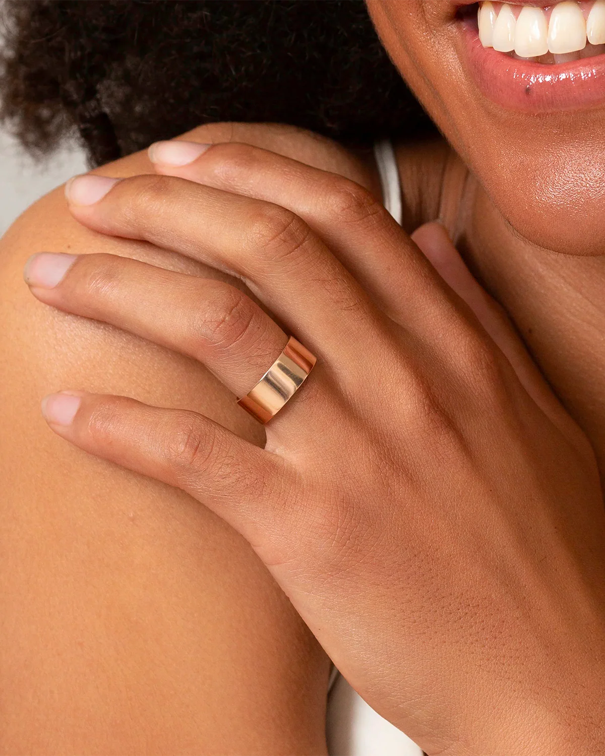 Smiling woman showcasing an Omlezo ring in gold color on her hand