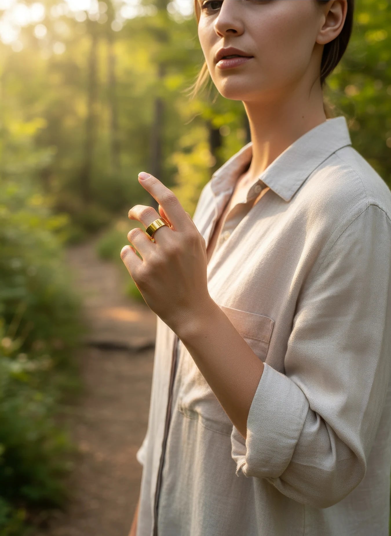 Smiling woman walking on a forest path wearing a gold Omlezo ring