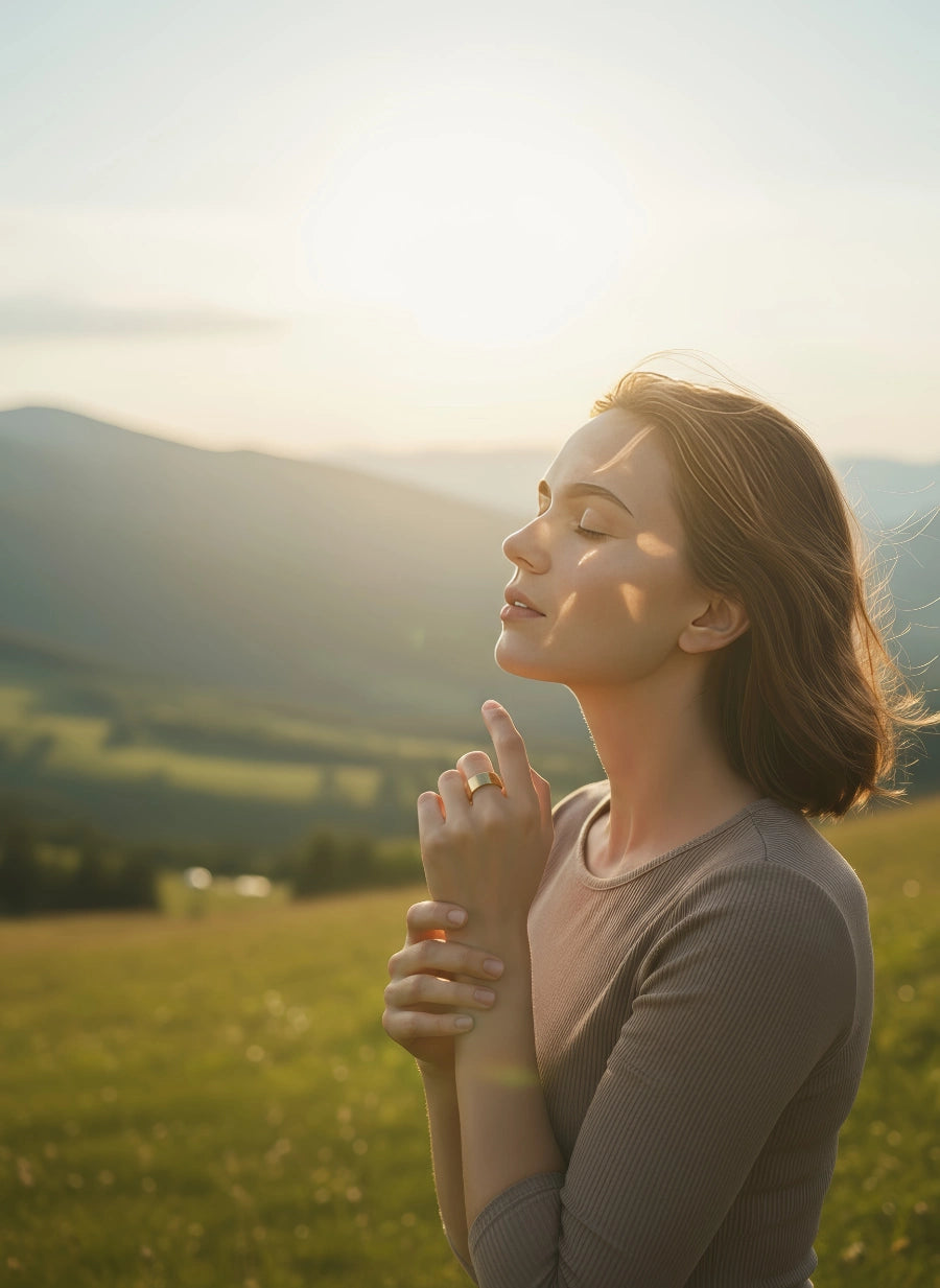 Smiling woman standing on the grass wearing a gold Omlezo Copper Magnetic Ring
