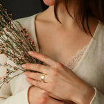 Omlezo Gold Magnetic copper ring worn on a woman's hand, holding flowers, showcasing its elegant design.