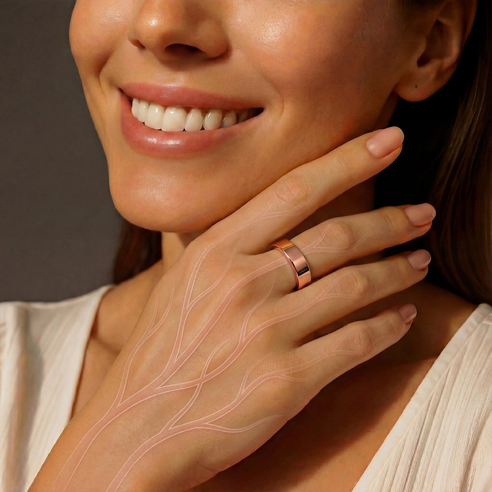 A woman smiling and showing a close-up of her hand wearing a omlezo rose gold magnetic copper ring, with soft pink nails.